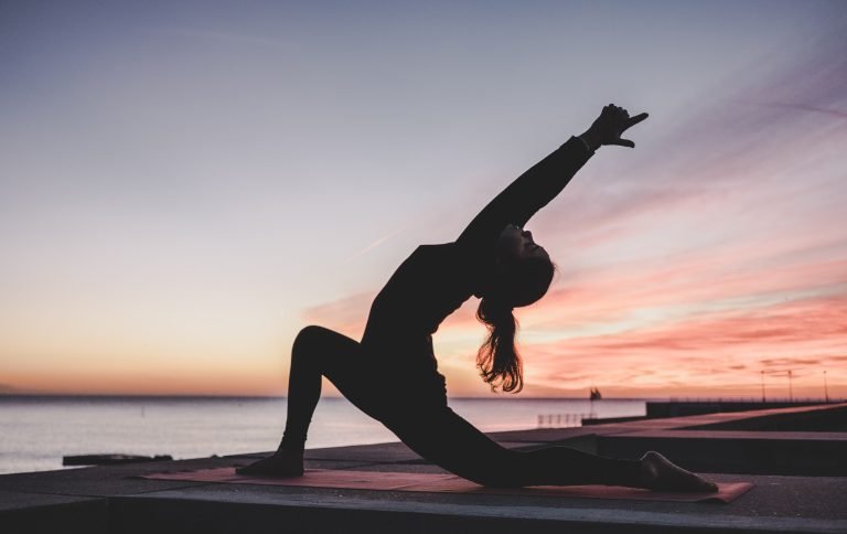 woman in a yoga pose with sunset in the background