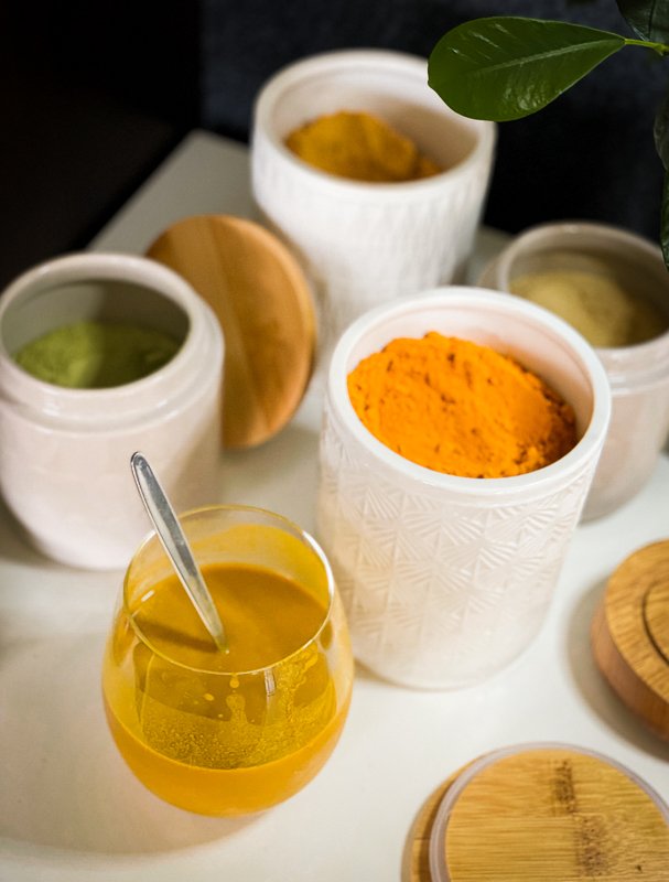 Golden Milk recipe in a glass, ceramic recipient containing powders of different colors